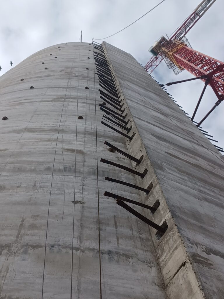 Structure de silo en béton avec supports métalliques et grue, vue en contre-plongée.